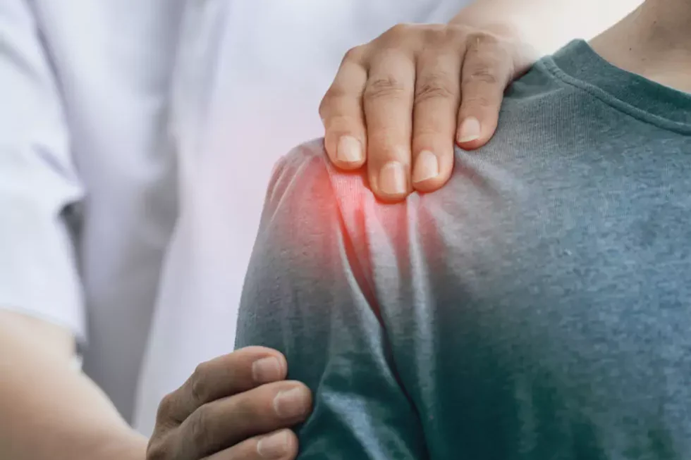 Physiotherapeut untersucht die schmerzende Schulter eines Patienten. Der schmerzende Bereich ist rot hervorgehoben.