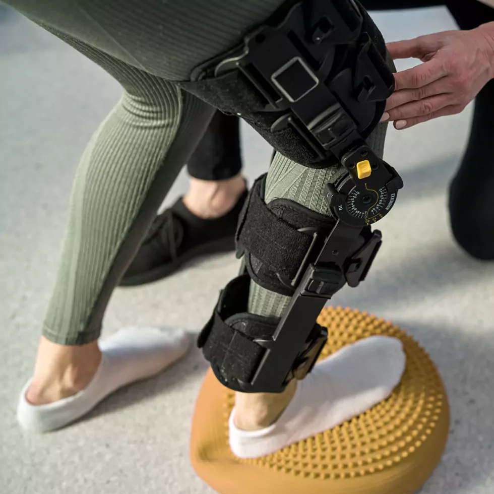 Junge Frau mit Orthese bei der Arbeit mit einem Physiotherapeuten