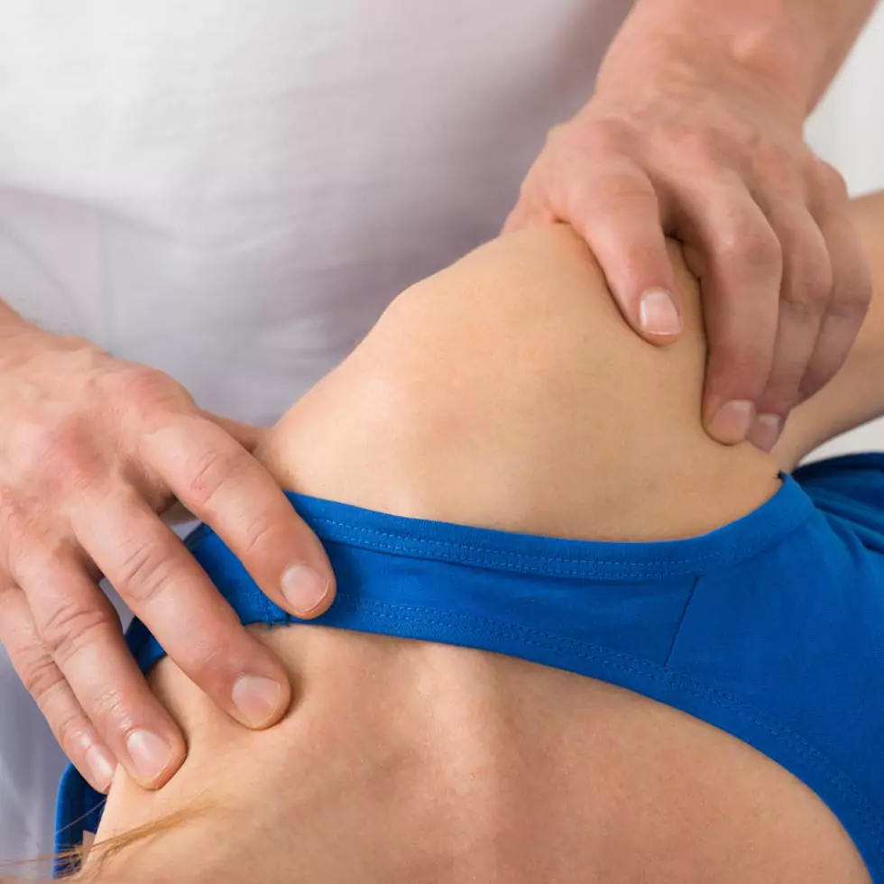 Nahaufnahme der Schulter einer Patientin, die von einem Therapeuten behandelt wird