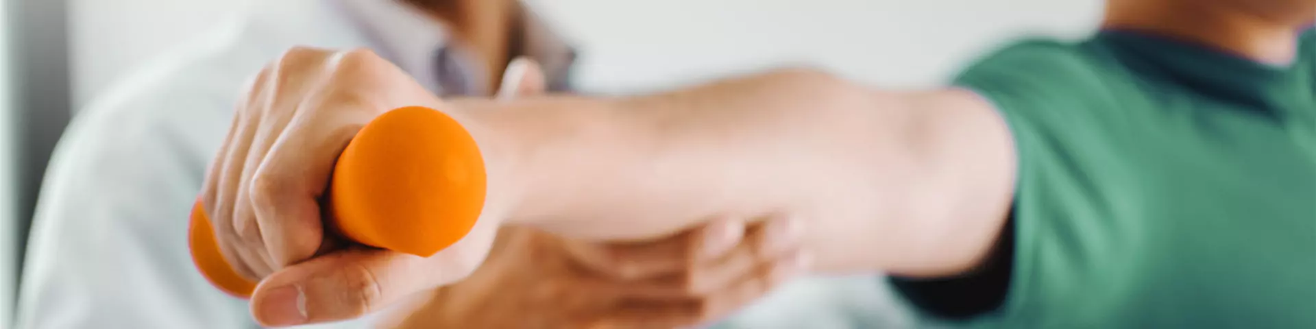 Physiotherapeut, der einen Patienten bei der Bewegung mit einer Hanteln unterstützt.