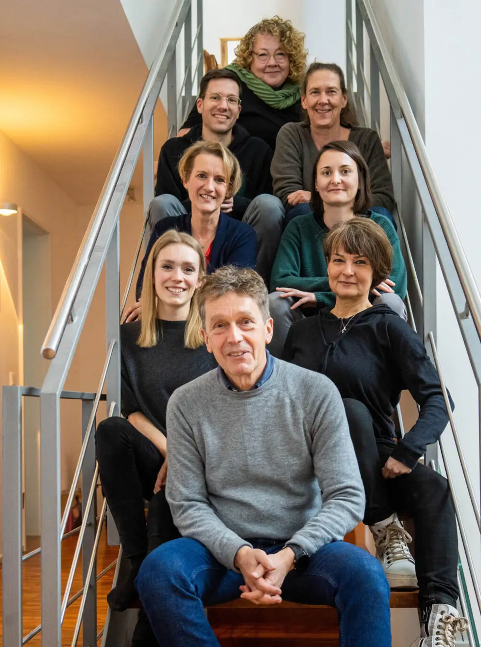 Gruppe von Menschen sitzt auf einer Treppe mit Metallgeländer in einem Innenraum